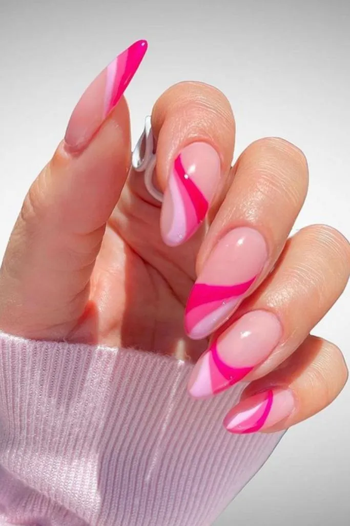 shot of a hand with long, pointed nails featuring a pink and white swirl design. 
