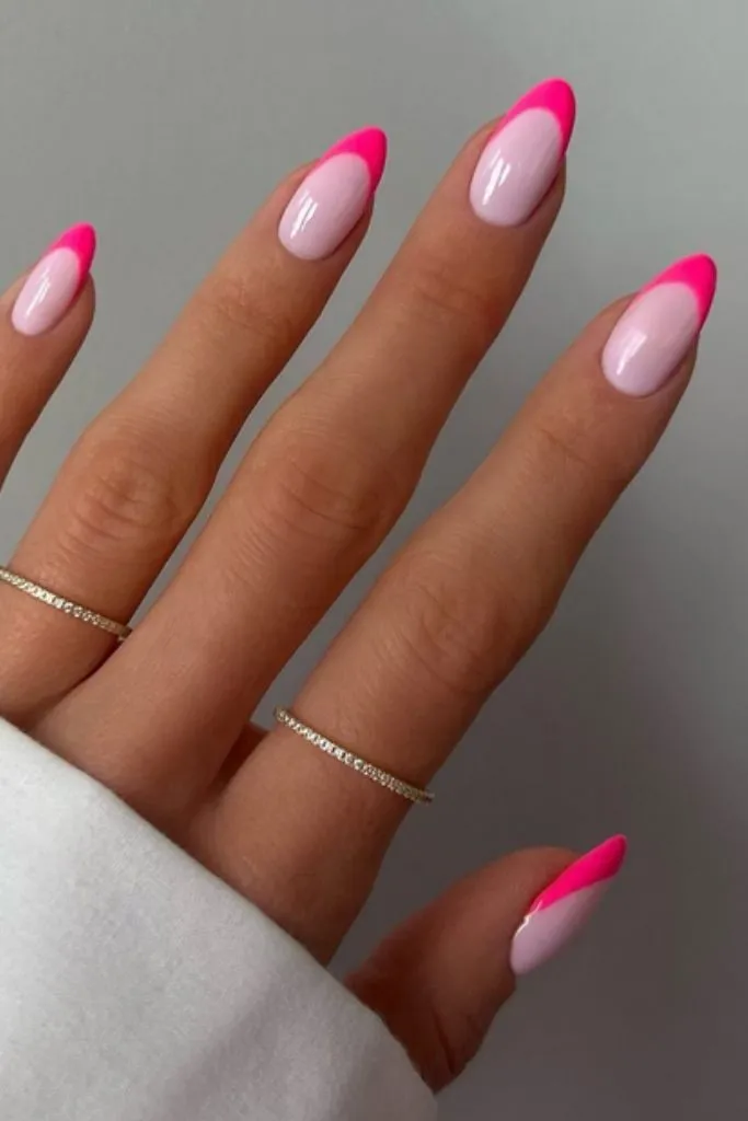 Pink French manicure with bright pink tips and gold rings.