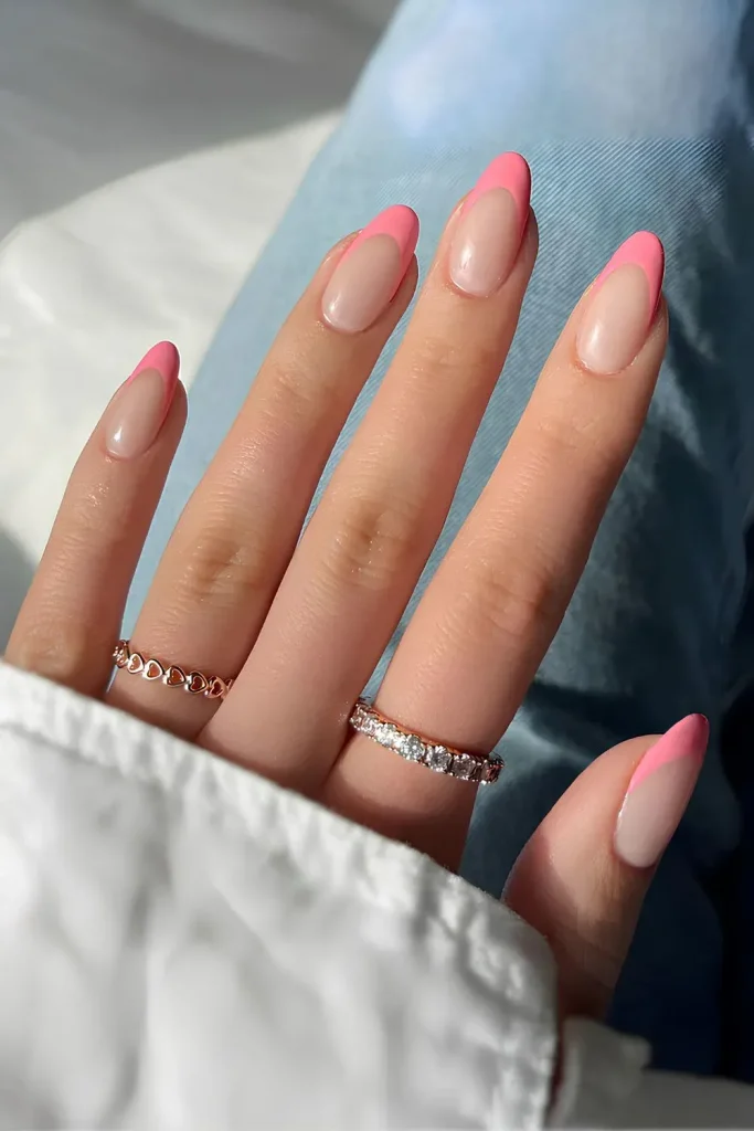 a modern take on the classic French tip with vibrant coral pink edges on almond-shaped nails.