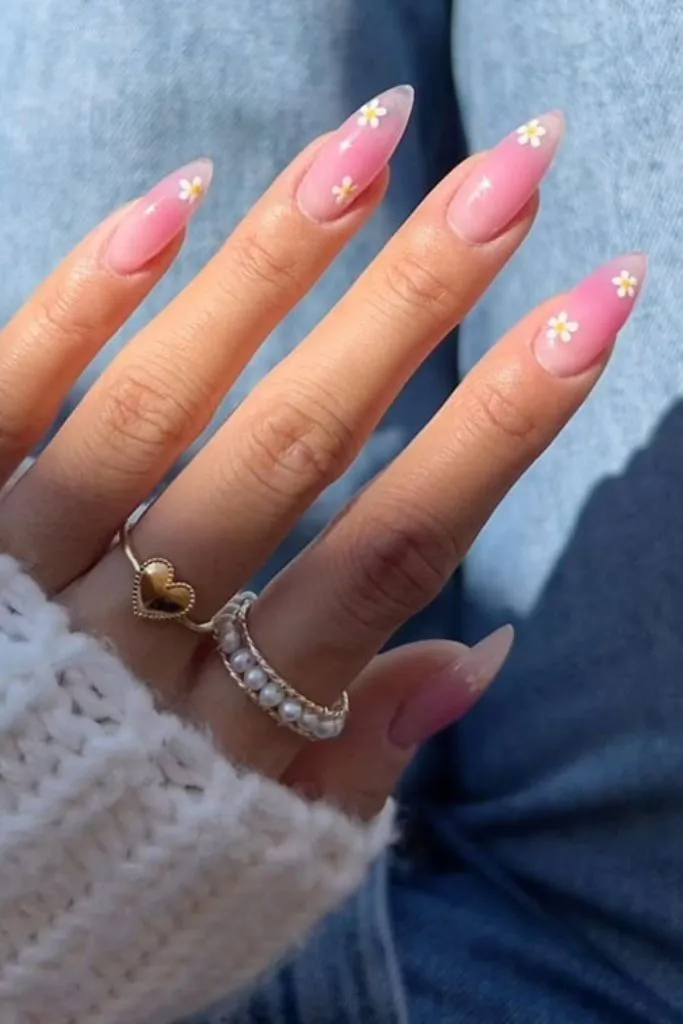 nail design features soft pink, almond-shaped nails with a delicate floral touch.