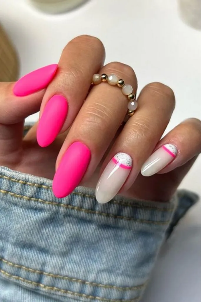  a hand with manicured nails featuring a combination of bright pink and white designs. 