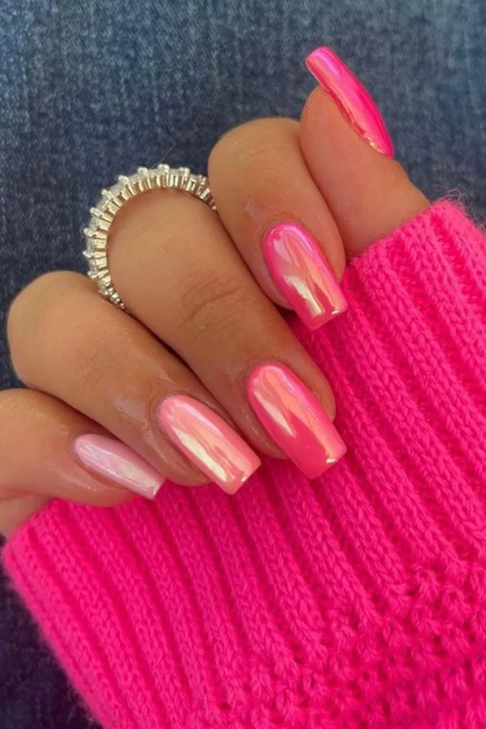 Pink iridescent nails with a silver ring on a finger.