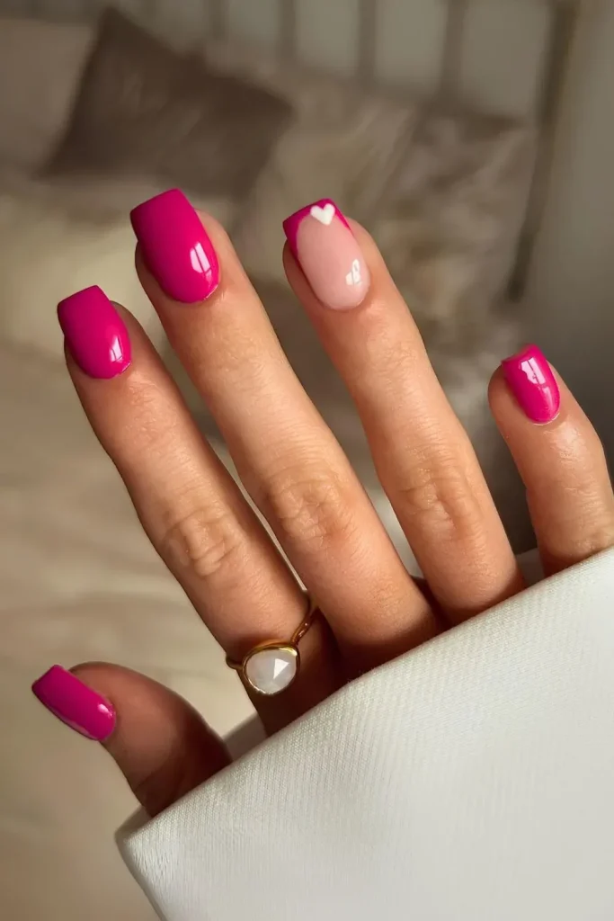 Pink nails with white heart accent on one nail.