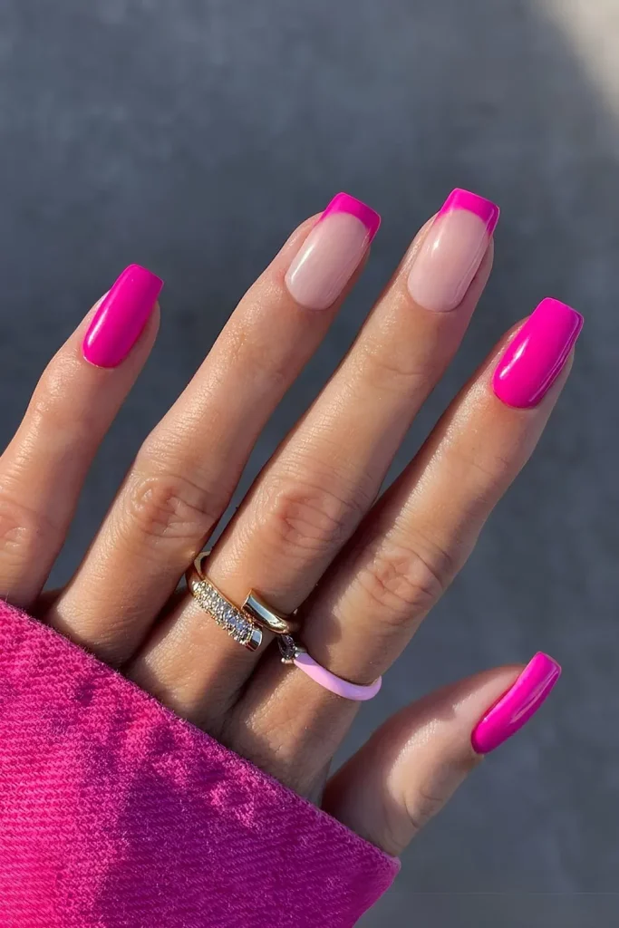 Pink French manicure with bright pink nails and gold rings.