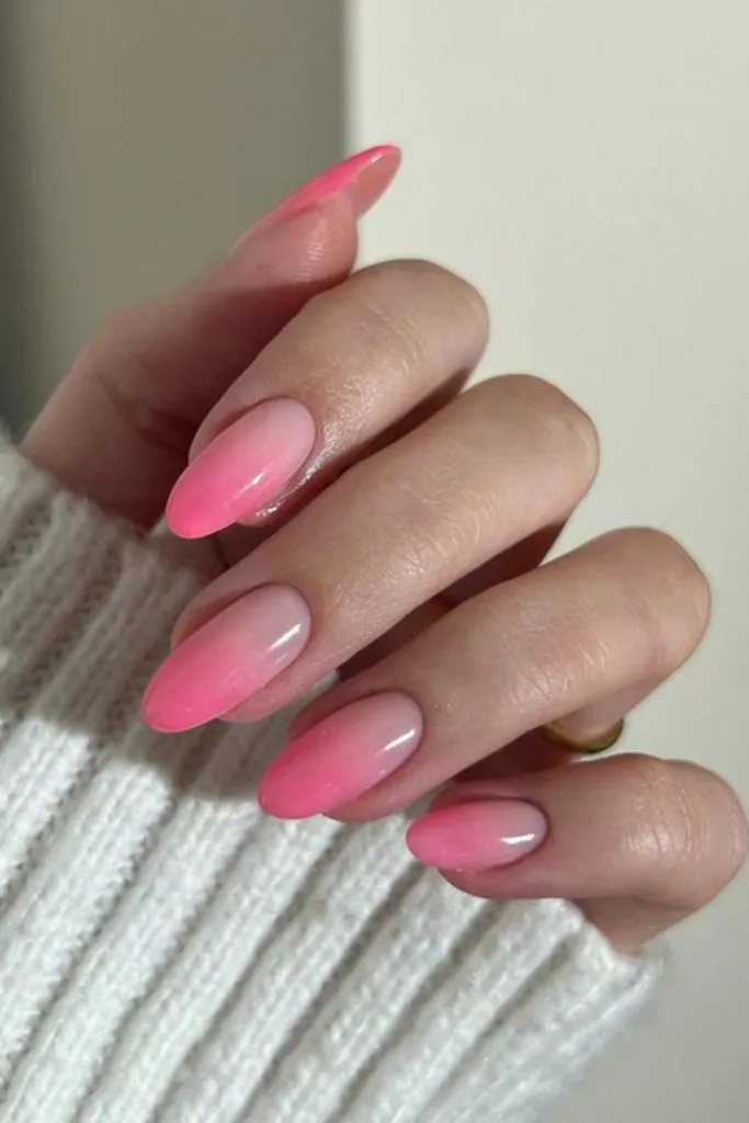 Pink ombre nails on long, almond-shaped nails.