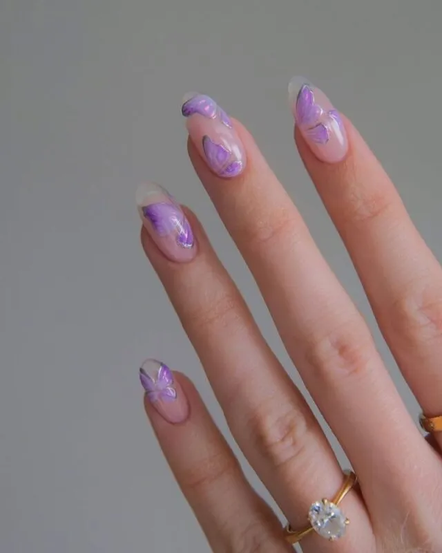 A delicate nail design featuring soft purple shades with intricate butterfly decals on a glossy finish.
