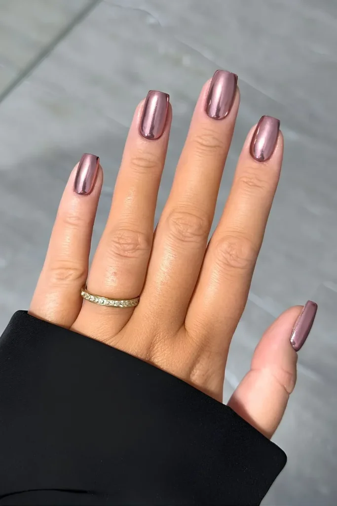 a sophisticated manicure featuring long, sleek nails with a reflective rose gold chrome finish, exuding a chic and modern vibe.