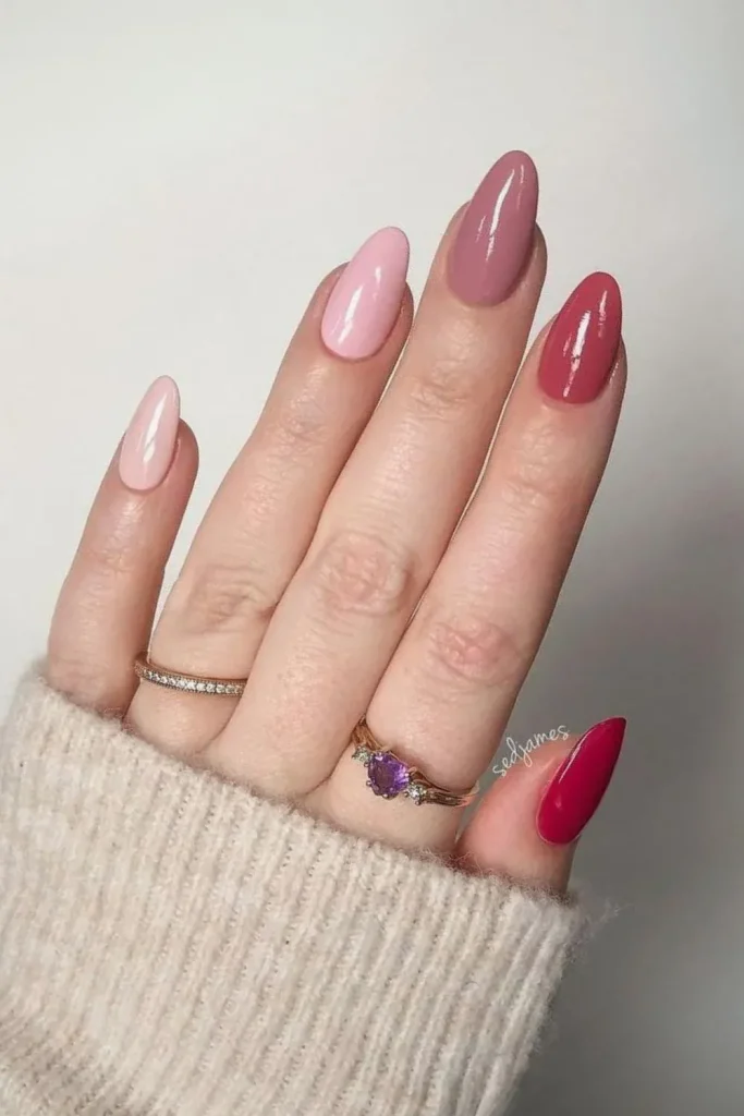 Pink gradient nails with gold rings on a hand.