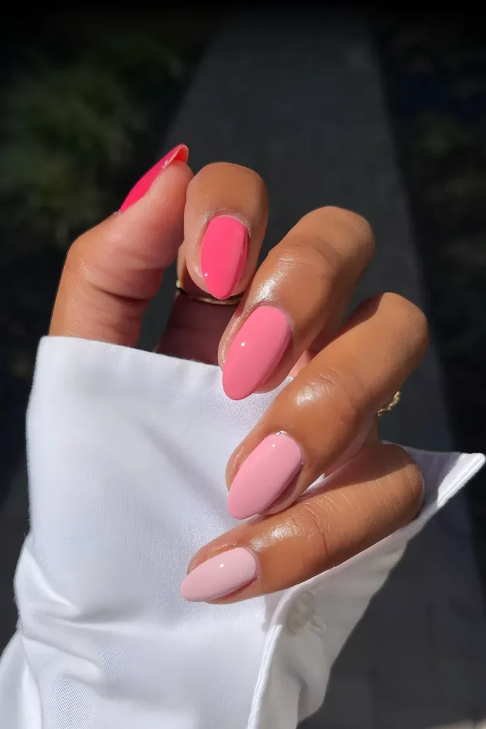 Pink gradient nails on a hand against a white fabric.