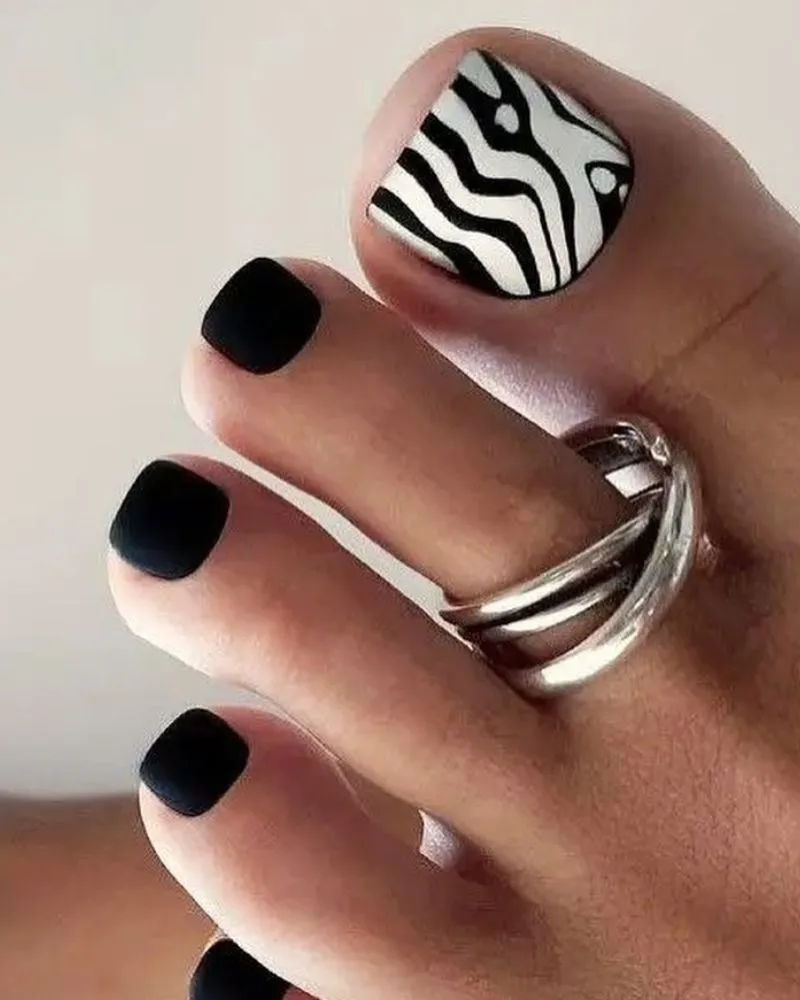 Chic black and white abstract toenail design with a glossy finish, featuring bold patterns for a modern and stylish pedicure look